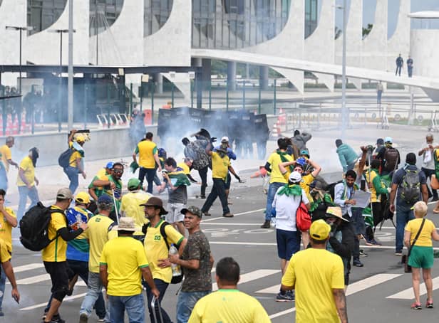 <p>Supporters of Brazilian former President Jair Bolsonaro clash with the police during a demonstration outside the Planalto Palace in Brasilia on January 8, 2023. - Brazilian police used tear gas Sunday to repel hundreds of supporters of far-right ex-president Jair Bolsonaro after they stormed onto Congress grounds one week after President Luis Inacio Lula da Silva's inauguration, an AFP photographer witnessed. (Photo by EVARISTO SA / AFP) (Photo by EVARISTO SA/AFP via Getty Images)</p>