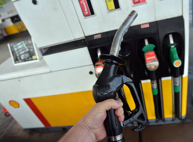 <p>A man poses holding a petrol pump nozzle at a filling station in Birkenhead, north-west England.  (Photo credit should read PAUL ELLIS/AFP via Getty Images)</p>