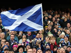 A Scotland fan waves a national flag as they enjoy the pre-match atmosphere prior to a Six Nations Rugby match at Murrayfield Stadium