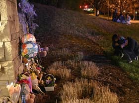 People gather at a makeshift memorial for victims outside the Covenant School building at the Covenant Presbyterian Church following a shooting, in Nashville, Tennessee, on March 27, 2023. - A heavily armed former student killed three young children and three staff in what appeared to be a carefully planned attack at a private elementary school in Nashville on Monday, before being shot dead by police. Chief of Police John Drake named the suspect as Audrey Hale, 28, who the officer later said identified as transgender. (Photo by Brendan SMIALOWSKI / AFP) (Photo by BRENDAN SMIALOWSKI/AFP via Getty Images)