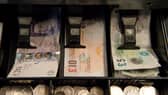 An open cash register containing pound coins and notes is pictured in a convenience store in London