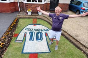 Bryn Nicholls stands next to the Jude Bellingham England shirt mural he has created in his front garden.