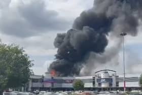 Flames rage through factory as plumes of smoke rise into air.