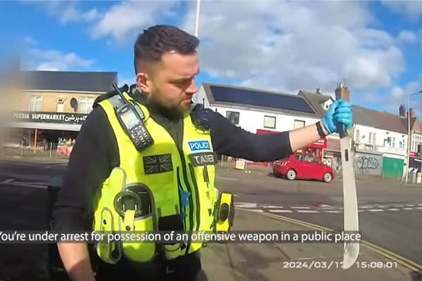 Police officer pulls huge machete from dealer's coat.