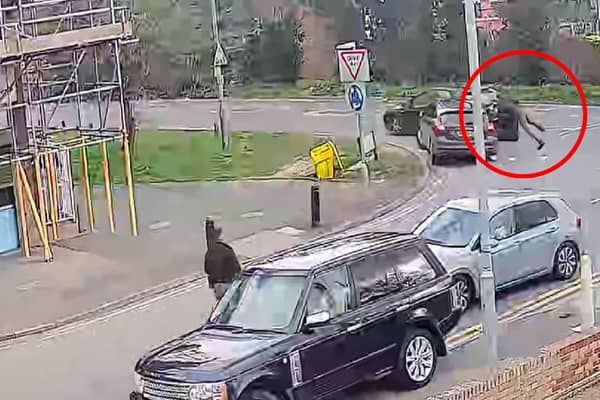 Police officer clings to car roof as suspect speeds off.