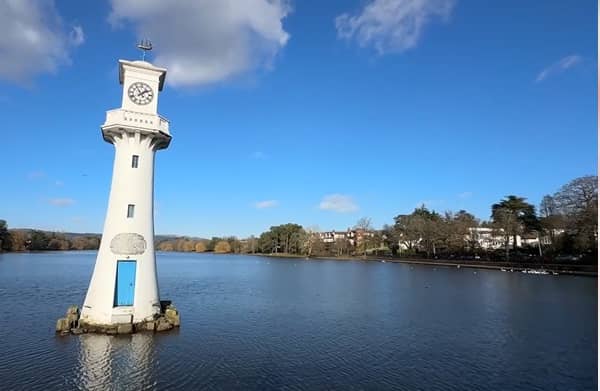 A white clock tower surrounded by water in a serene location