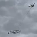 Helicopter carrying large metal circle.