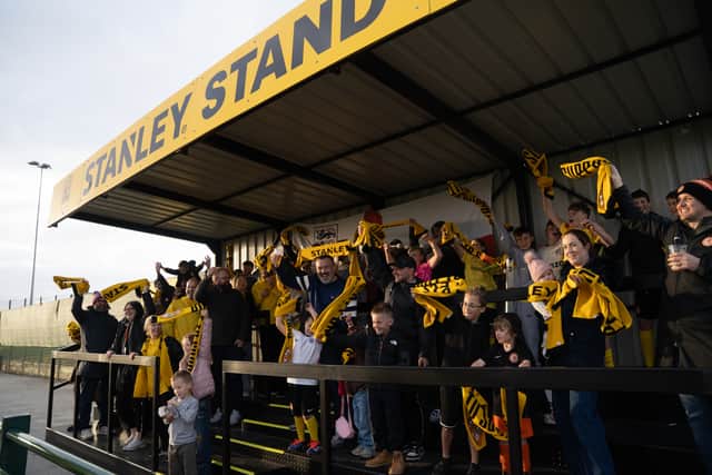 Rugby Borough FC supporters wave their free matchday scarves in the new STANLEY® Stand, built by the club's own players, coaches and volunteers from the trades, on its opening day at the club's Kilsby Lane ground.