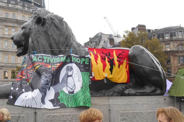 XR Protesters' banners are hung off one of the Landseer Lion statues in Trafalgar Square as