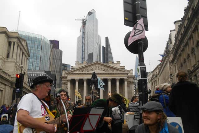 Chris Philpott plays a song as part of the Extinction Rebellion protest in front of the Bank of England calling for a withdrawal of subsidies given by the government to support fossil fuel industries.