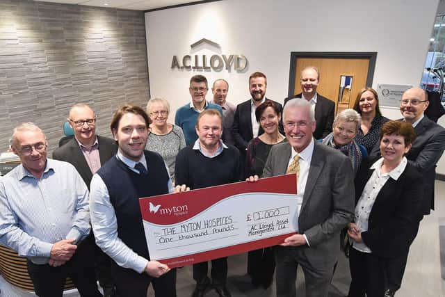 Chris Willmott from The Myton Hospices (front, left) receives a cheque for 1,000 from Alistair Clark of AC Lloyd Homes (front, right) watched by staff at its headquarters in Warwick