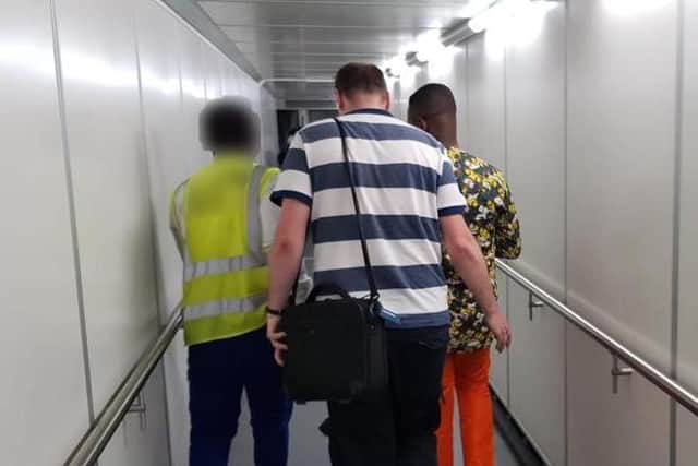 Det Sgt Gareth Unett leading Ransford Buabeng to the plane in Ghana. Photo supplied by Warwickshire Police