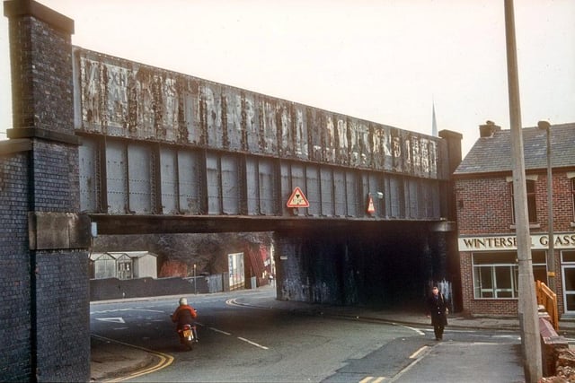 This picture shows the junction of Waterloo Road and Tulketh Brow, in Ashton, Preston in 1984. Located due west of Maudland Viaduct is this bridge that carries the Fylde coast railway line over Waterloo Road. Known for generations as 'the danger bridge'. The word 'Danger' was once painted in bold yellow letters on both sides of the bridge to warn traffic of the height restriction. Over the years several buses and lorries came to grief attempting to pass below the structure. The bridge has since been re-built easing the overhead restriction from 11' 9'' to 14' 3'' and now features a roundabout on Tulketh Brow to help with the traffic passing to and from the city centre. Photo: Beth Hayes, courtesy of the Preston Historical Society