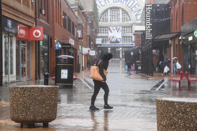 A shopper makes their way through the driving rain.