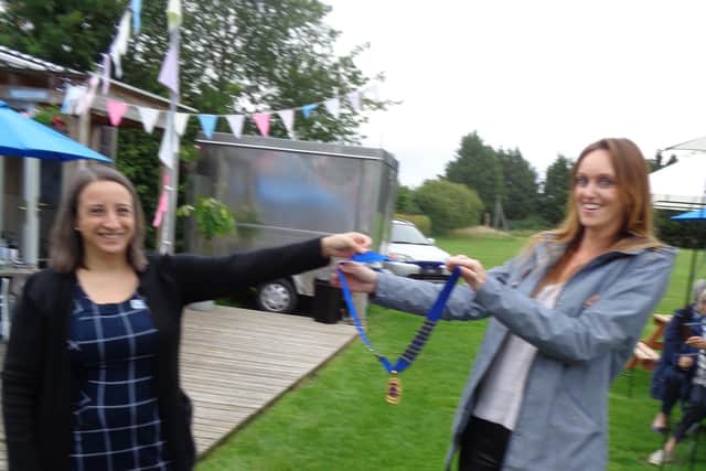 Outgoing President Tamara Friedrich, while socially distanced, handed over her chain of office to new President Hannah Johnson. Photo by Warwick Lions