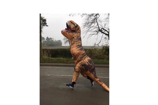 Joshua Evans jogging in an eight-foot dinosaur costume as part of his Movember Madness fundraising efforts.