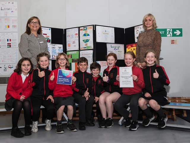 Katie Gane, Priors Field School's headteacher (left) with its modern foreign languages lead Nelly Cain (right) and pupils with the certificate for the British Council International School Award.