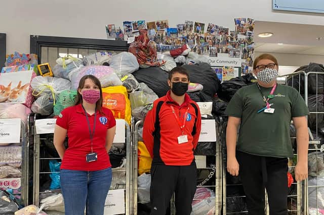 Members of Warwickshire Search and Rescue Rachel and Connor with Leamington Morrisons community champion Alexandra Pearson in front of the clothing and toys donations made to the store to support Afghan refugee families and The British Red Cross.