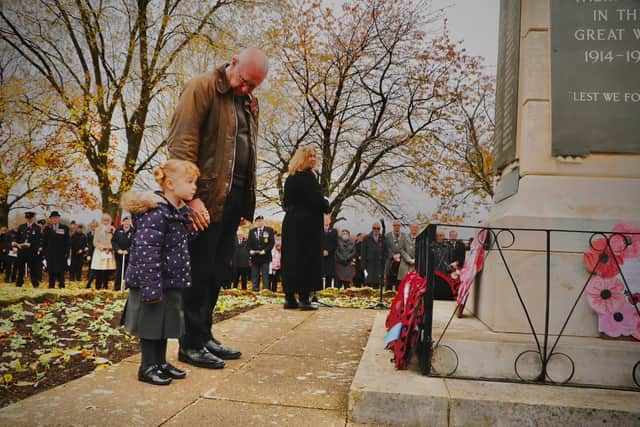 Sophie Cartwright, aged four, lays a wreath on behalf of her fellow Poppy Appeal volunteers as her grandfather and former serviceman Mark watches on at the war memorial in Kenilworth on Remembrance Sunday.