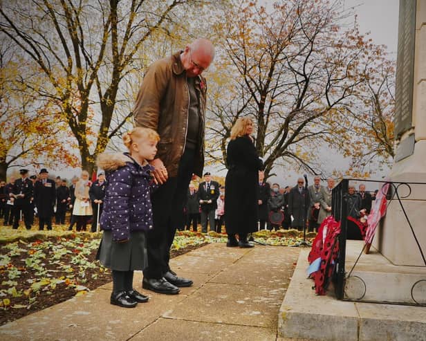 Sophie Cartwright, aged four, lays a wreath on behalf of her fellow Poppy Appeal volunteers as her grandfather and former serviceman Mark watches on at the war memorial in Kenilworth on Remembrance Sunday.