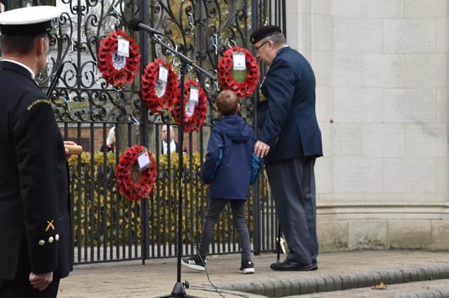 Grandfather and grandson walk up together to place a wreath.