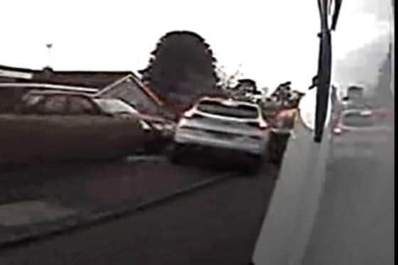 A still from the video which shows a driver mounting the pavement to get around the refuse vehicle - and nearly hitting a worker.
