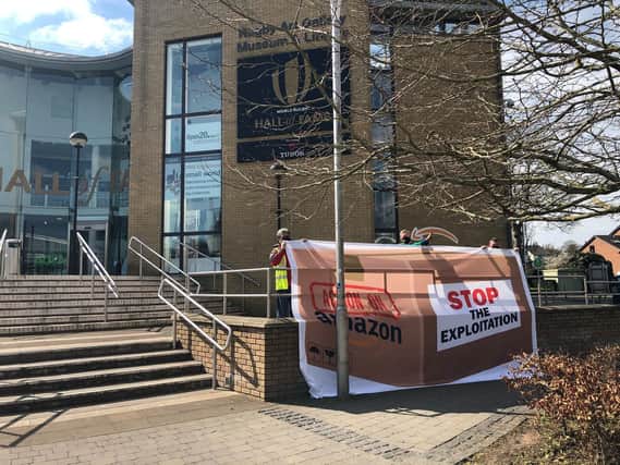 Campaigners unfurl the banner outside the library. Photo courtesy of Unite.