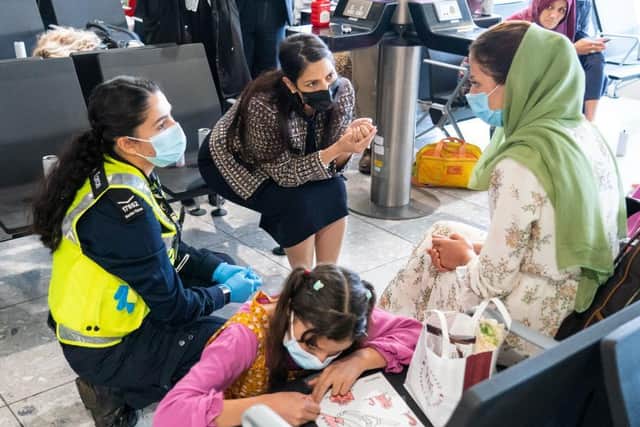 LONDON, ENGLAND - AUGUST 26: Home Secretary Priti Patel (2nd left) talking to Malalai Hussiny (wearing green headscarf) a refugee from Afghanistan who arrived on a evacuation flight at Heathrow Airport on August 26, 2021 in London, England. Ministry of Defence figures put the number of people evacuated by the UK since August 13 at 9,226, but there are thousands feared to be remaining. Foreign Secretary Dominic Raab has said the UK will use "every hour" left to evacuate people from Afghanistan as he declined to rule out British troops having to leave by the end of Friday. (Photo by Dominic Lipinski - WPA Pool/Getty Images)