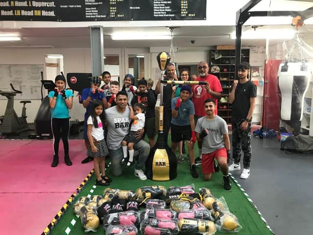 Spabar CEO Jazz Gill with Leamington Community Boxing head coach Babs Kandola, the donated equipment, and the members of one of the club's youth classes.