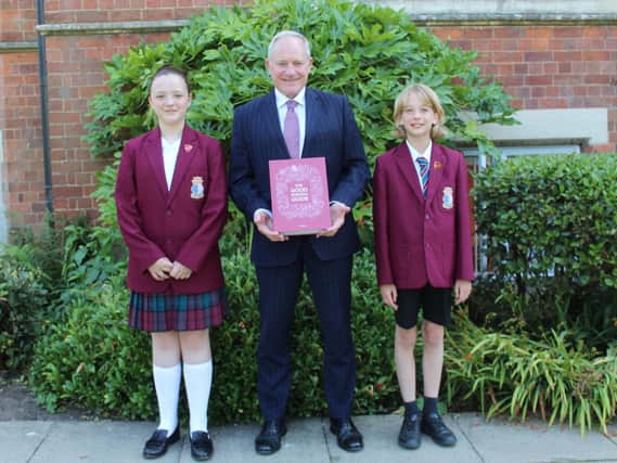 Crackley Hall pupils Lily Bryson and Aaron Anderson with Headmaster Rob Duigan who is holding a copy of the Good Schools Guide