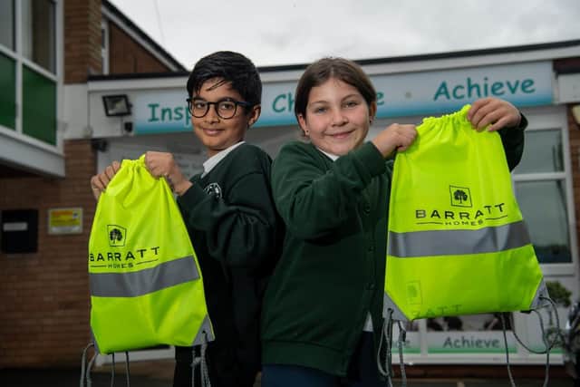 Two pupils outside Bilton C of E Junior School with their kit bags donated by Barratt Homes.