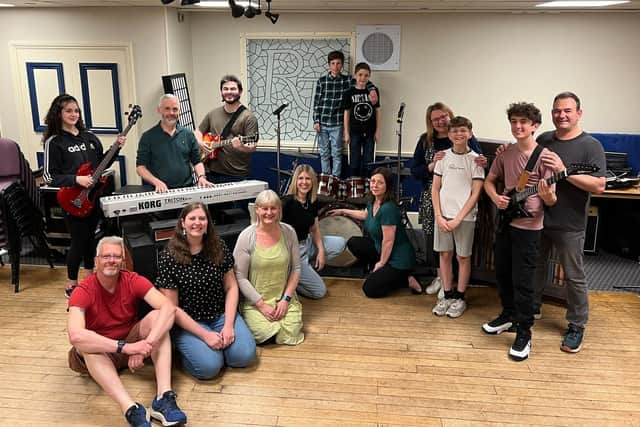 In front of the keyboard are Kevin Bright (teacher/parent/Stanley), Kirsty Bright (KC/teacher) and assistant director Emma Bright; behind the keyboard are Mabel Watson (Katie Travis, team Stick It To The Man), musical director Jon Watson and Matt Watson (Dewey Finn, team Stick It To The Man); on the left behind the drums in checked shirt is Rafferty Jones (Freddy Hamilton, team Stick It To The Man) with Leanne Jones (parent/teacher) in front of him; on the right behind drums is Riley Withall (Freddy Hamilton, team Mount Rock) and Gwen Withall (parent/ JJ/ school staff) in front of him; next to her are Sophie Jones (Mrs Sheinkopff) and Alfie Jones (Billy Sandford, Team Mount Rock); and on the right are Dexter Robinson (Zack Mooneyham, team Stick It To The Man) and director Kenny Robinson. Not in the photo are Poppy Goodwin (Lauren Turner, team Stick it to the Man) and Dave Goodwin (parent / teacher).