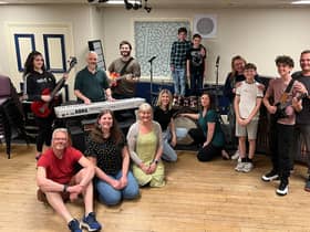 In front of the keyboard are Kevin Bright (teacher/parent/Stanley), Kirsty Bright (KC/teacher) and assistant director Emma Bright; behind the keyboard are Mabel Watson (Katie Travis, team Stick It To The Man), musical director Jon Watson and Matt Watson (Dewey Finn, team Stick It To The Man); on the left behind the drums in checked shirt is Rafferty Jones (Freddy Hamilton, team Stick It To The Man) with Leanne Jones (parent/teacher) in front of him; on the right behind drums is Riley Withall (Freddy Hamilton, team Mount Rock) and Gwen Withall (parent/ JJ/ school staff) in front of him; next to her are Sophie Jones (Mrs Sheinkopff) and Alfie Jones (Billy Sandford, Team Mount Rock); and on the right are Dexter Robinson (Zack Mooneyham, team Stick It To The Man) and director Kenny Robinson. Not in the photo are Poppy Goodwin (Lauren Turner, team Stick it to the Man) and Dave Goodwin (parent / teacher).