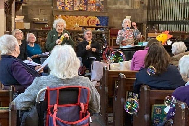 The picture shows a group of about 10 dementia volunteers as part of a gathering of 75 people, singing 'I'm For Ever Blowing Bubbles' If you look carefully you can see some of the bubbles which were blown all over the church.
