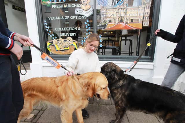 Rustic Food Cafe owner Alice and trainee guide dogs Charlie and Ashleigh with the mural in the background. Picture supplied.