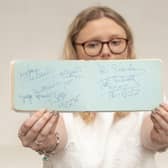 Emma Errington, a member of Hansons' team, holds up the autograph book showing the Beatles page on the left (Photo: Hansons)