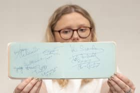 Emma Errington, a member of Hansons' team, holds up the autograph book showing the Beatles page on the left (Photo: Hansons)
