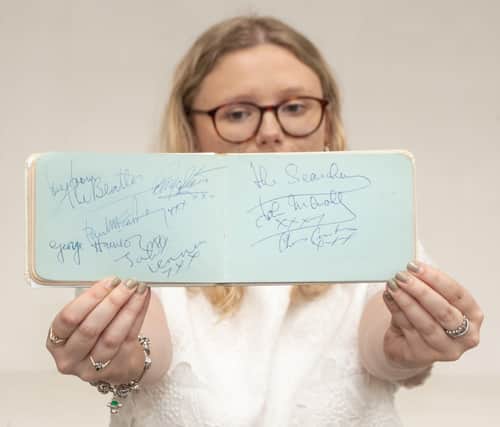 Emma Errington, a member of Hansons' team, holds up the autograph book showing the Beatles page on the left (Photo: Hansons)