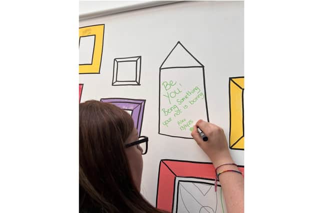 Alex Pearson, community champion at Leamington Morrisons, writing on the new 'community wall'. Photo supplied