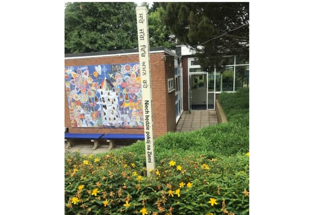 The Peace Pole at All Saint's Junior School in front of a mural designed by the children. Photo supplied