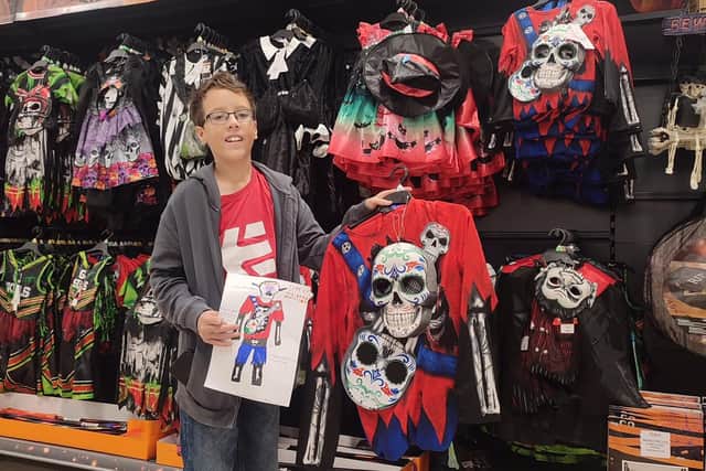 Étienne holding his costume and his design in Tesco. Photo supplied