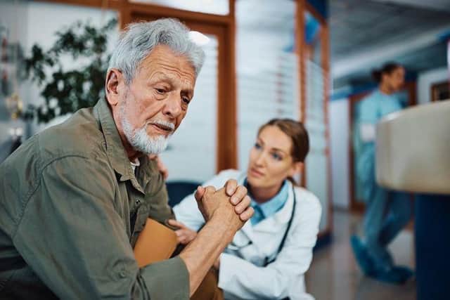 A white haired man appears upset as he is consoled by a doctor