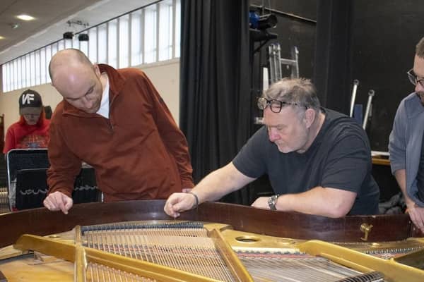 Steve Droy, professional concert piano tuner and founder of the Piano Technology School, works on the baby grand piano at the Benn Hall with students Eoin McCarthy (left) and Henry Melbourne (right)