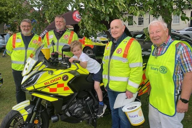 Alex Haynes (aged six) from Leamington Spa tries out a Blood Bike, one of charities being supported by Leamington Rotary Club this year. Warwickshire and Solihull Blood Bikes provides a rapid response medical transport service to the NHS, free of charge. (Left to right) Paul Sheehan, Jonathon Smith, fleet manager, and Don O'Brien, events manager, with Rotarian Barry Andrews.