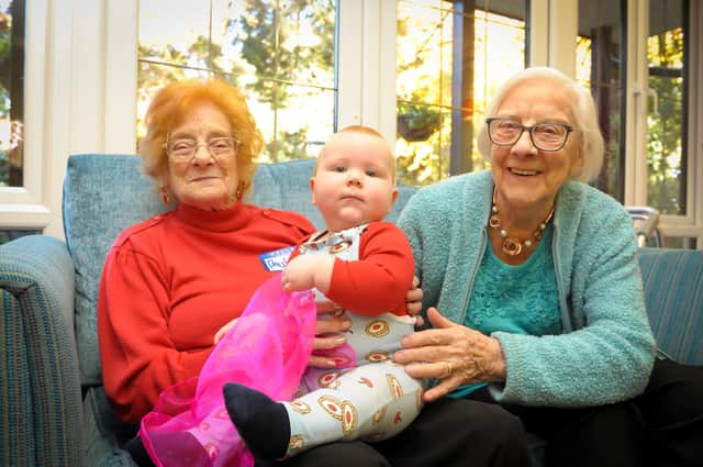 Residents Phyllis and Muriel enjoy a cuddle with 10-month-old Elliott.