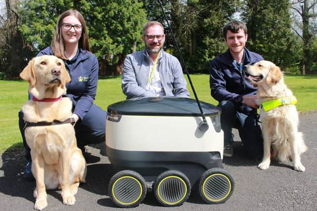 Representatives from Guide Dogs and Starship Technologies with trainee guide dogs and a robot