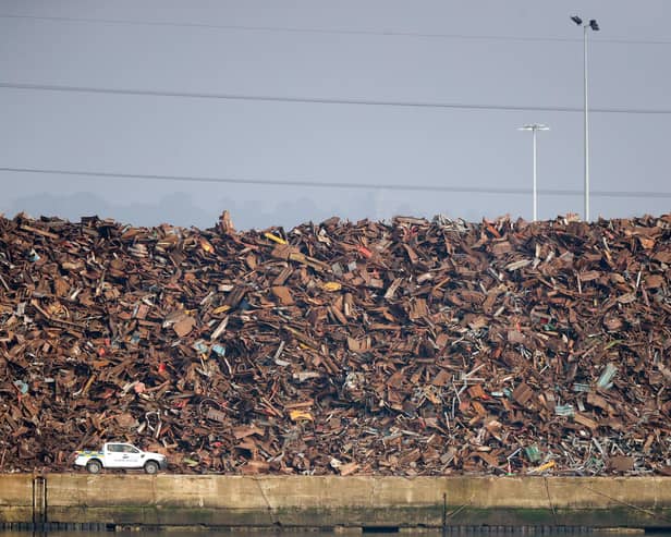 A vehicle passes a towering pile of scrap metal at Southampton port.