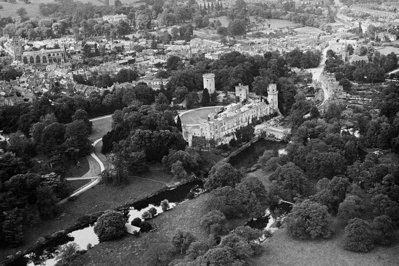 Warwick Castle from the air in 1920 with the River Avon in the foreground and the church and town beyond.