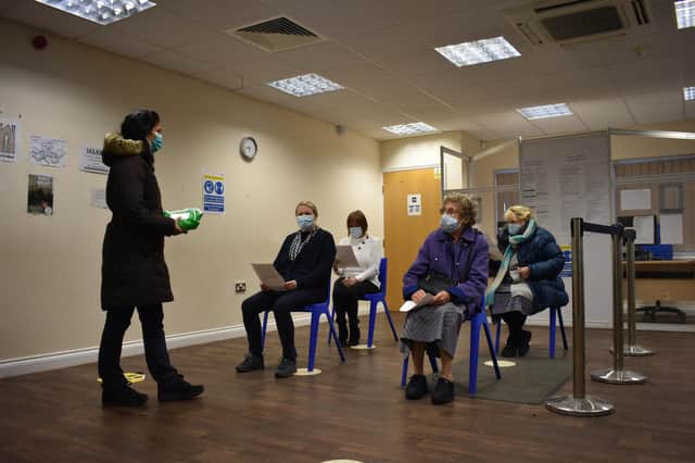 A volunteer helps some of the last people to be vaccinated before the centre is handed over to the NHS.