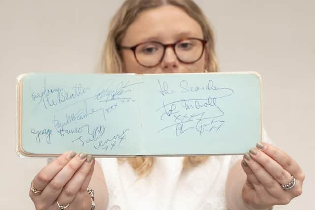 Emma Errington, a member of Hansons' team, holds up the autograph book showing the Beatles page on the left.